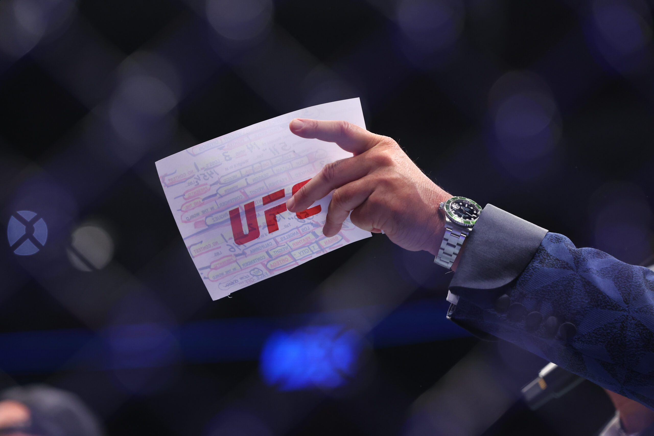 Grafika przedstawia kartkę konferansjera UFC - Bruce'a Buffera z napisem "UFC".